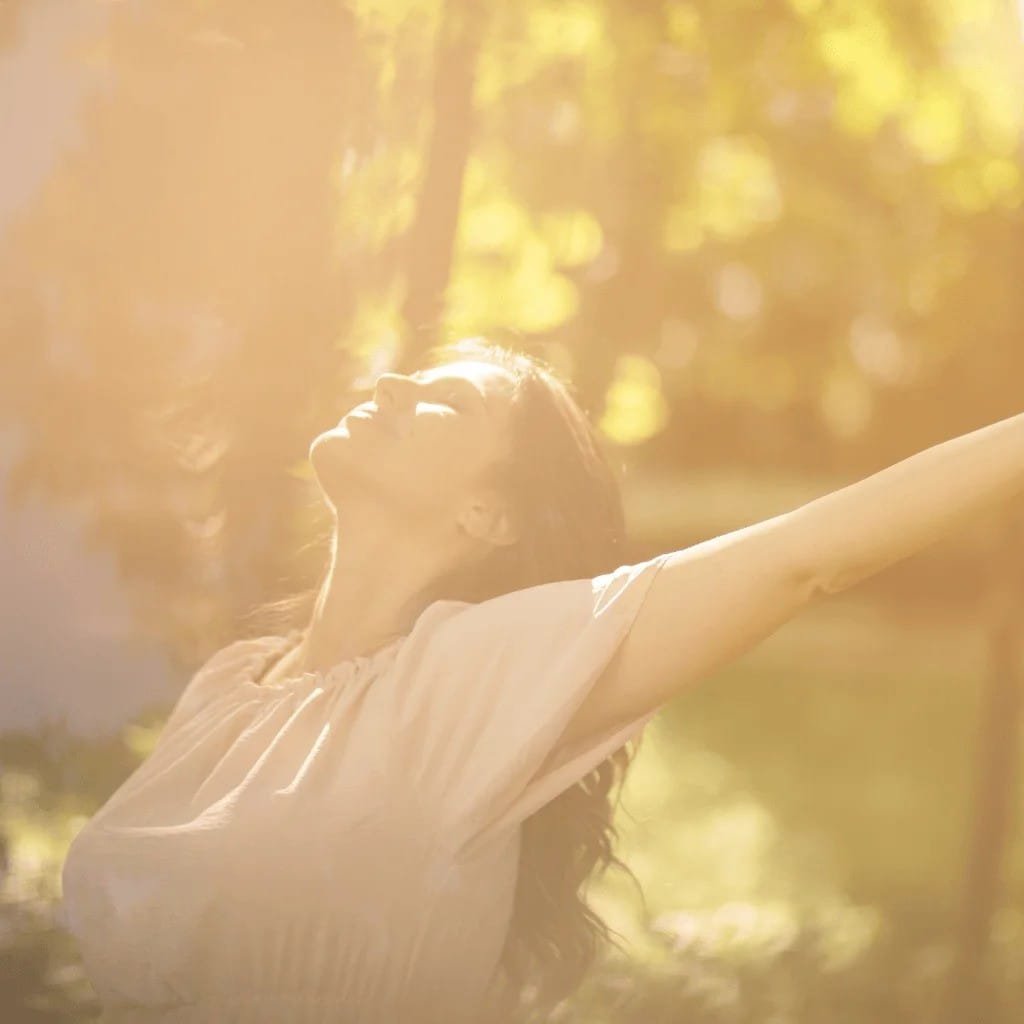 Woman enjoying the sunlight, symbolizing nature's healing