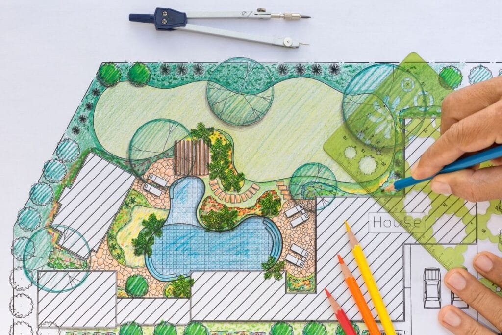 Hand sketching a landscape design with a pool, patio, and greenery