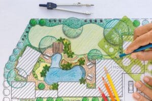 Hand sketching a landscape design with a pool, patio, and greenery