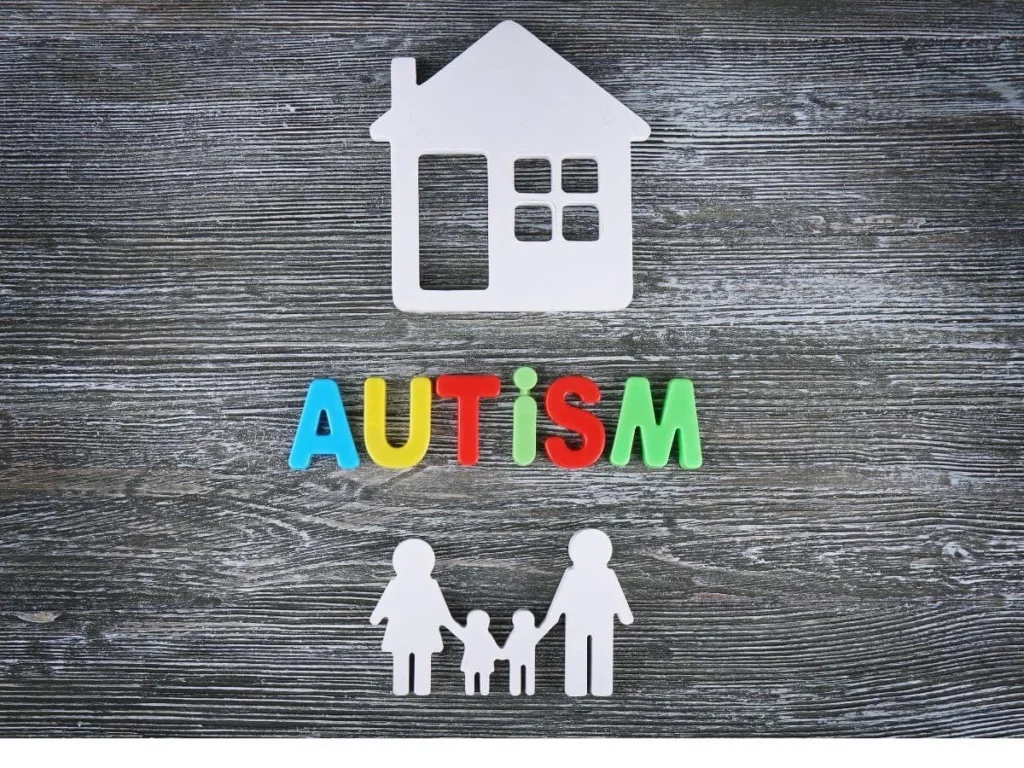 Colorful autism letters with a house icon and family figures on a wooden background